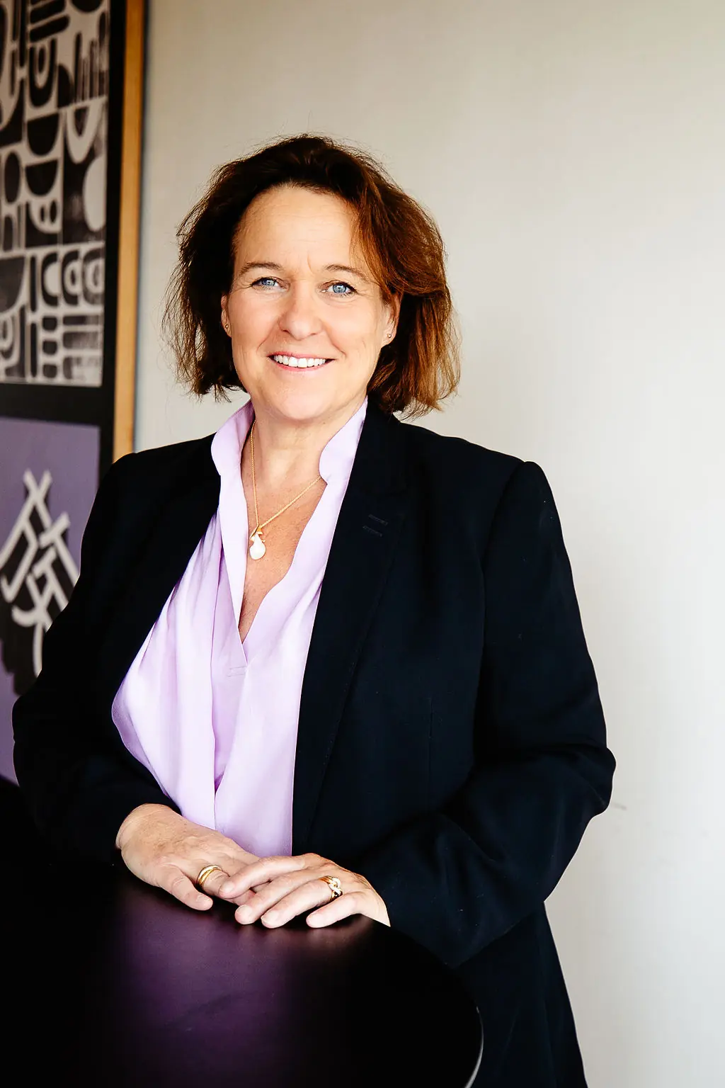 Kate Maat in a suit standing at a table